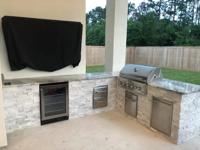 Outdoor kitchen with stainless steel grill and stone counters