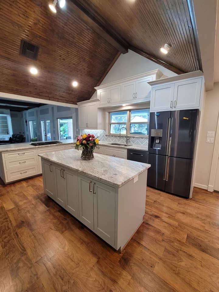 Modern white kitchen with large center island and stainless steel fridge